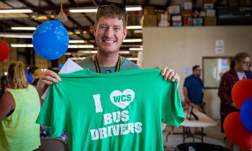 A bus driver holds up a t-shirt that reads \